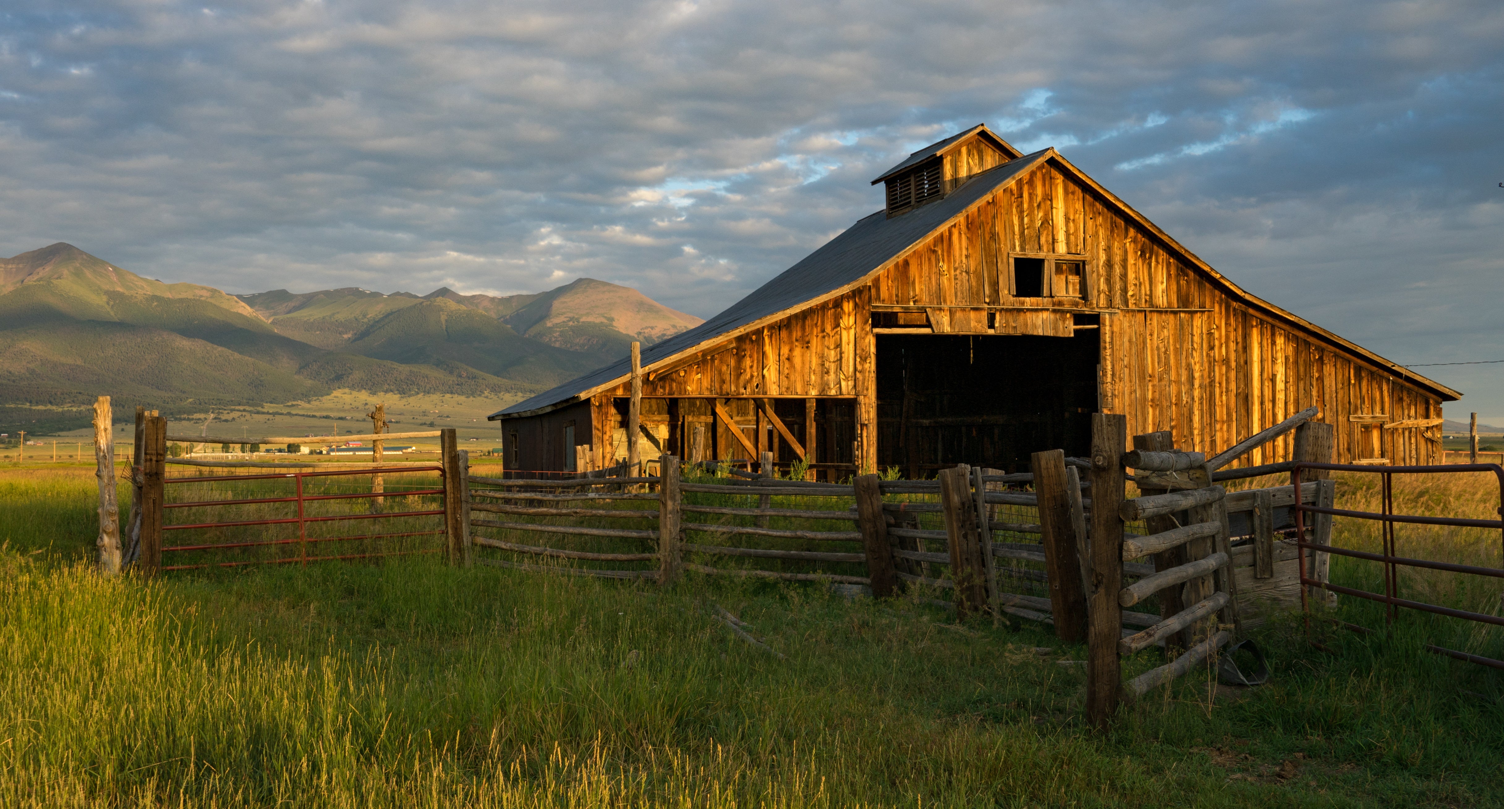 Old barn on a farm with mountains in the background.
