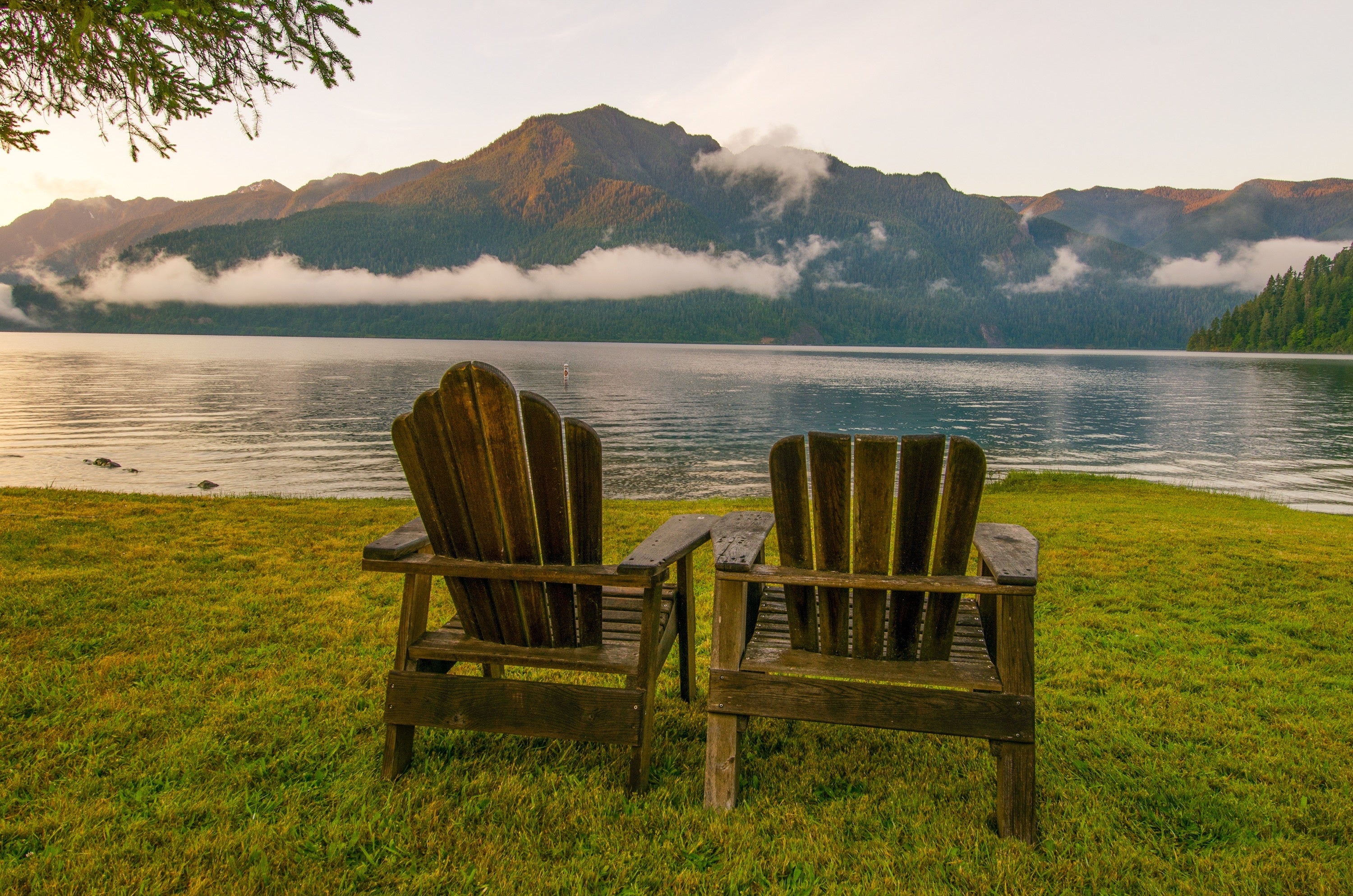Two adirondack chairs outside looking over the lake and mountains.