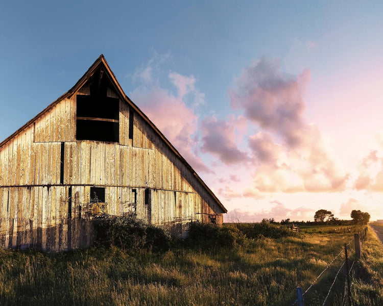 Wooden barn in a field with a colorful sky