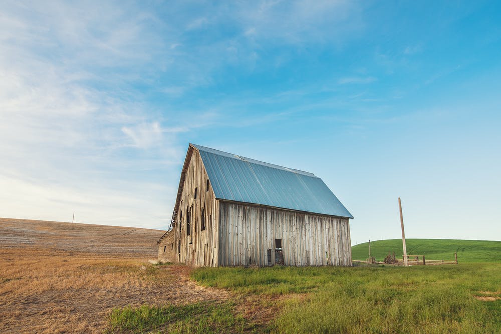 Beautiful landscape field with blue sky and an old barn.