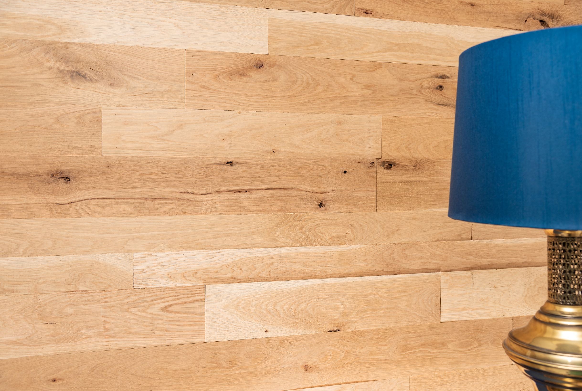 Rustic white oak wood DIY bedroom wall with a lamp on a side table.