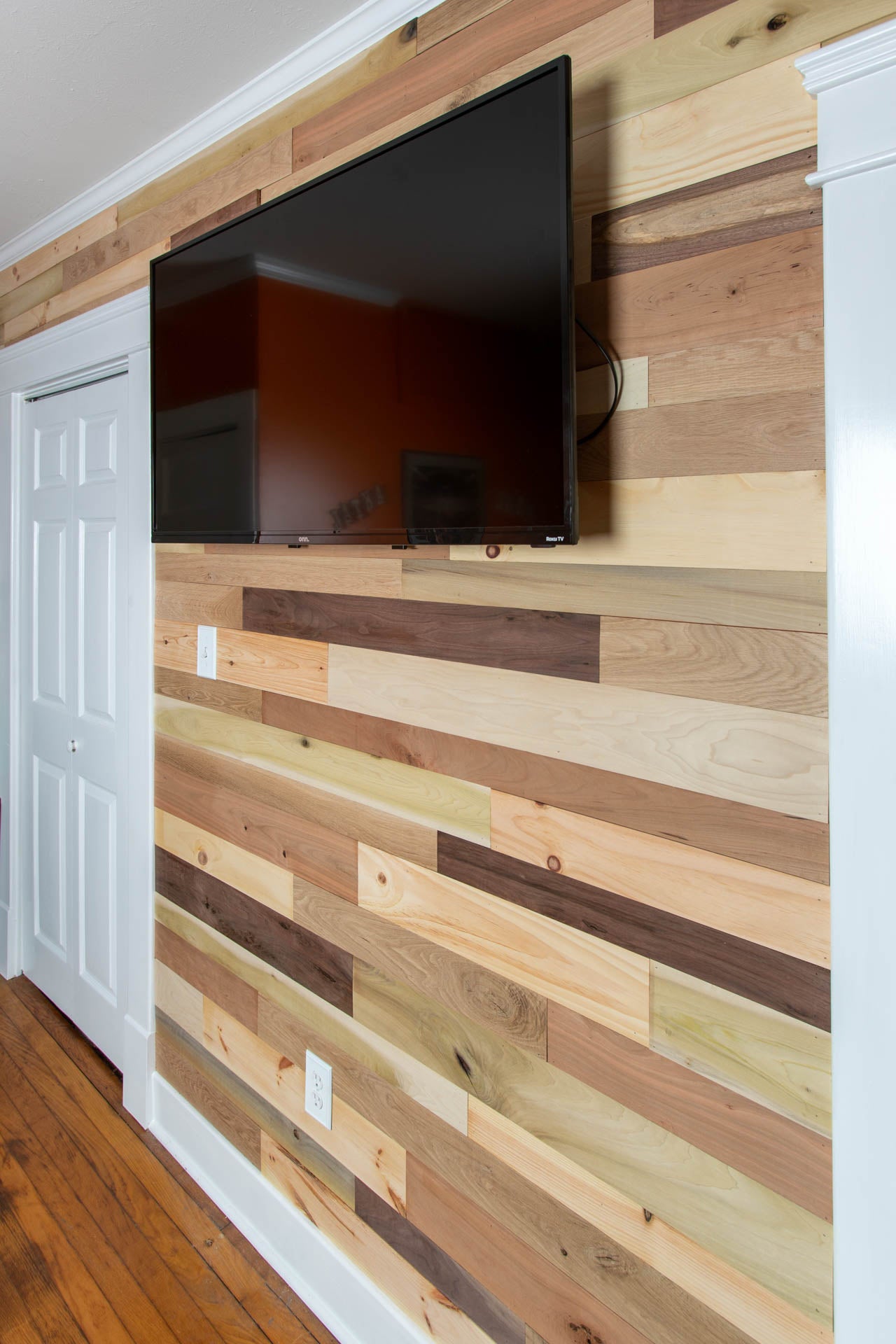 Vintage multicolored reclaimed wooden plank wall with a mounted TV.