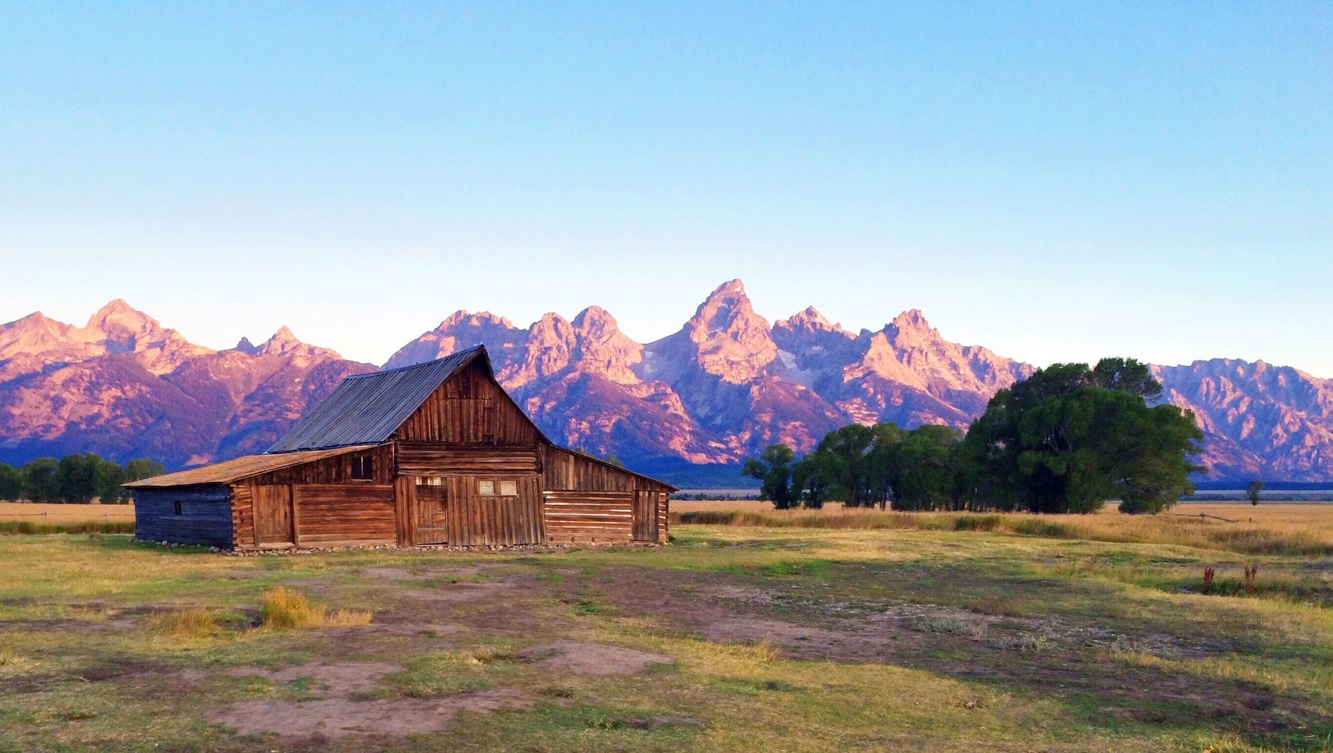 Beautiful farm house on a ranch with mountains in the background.