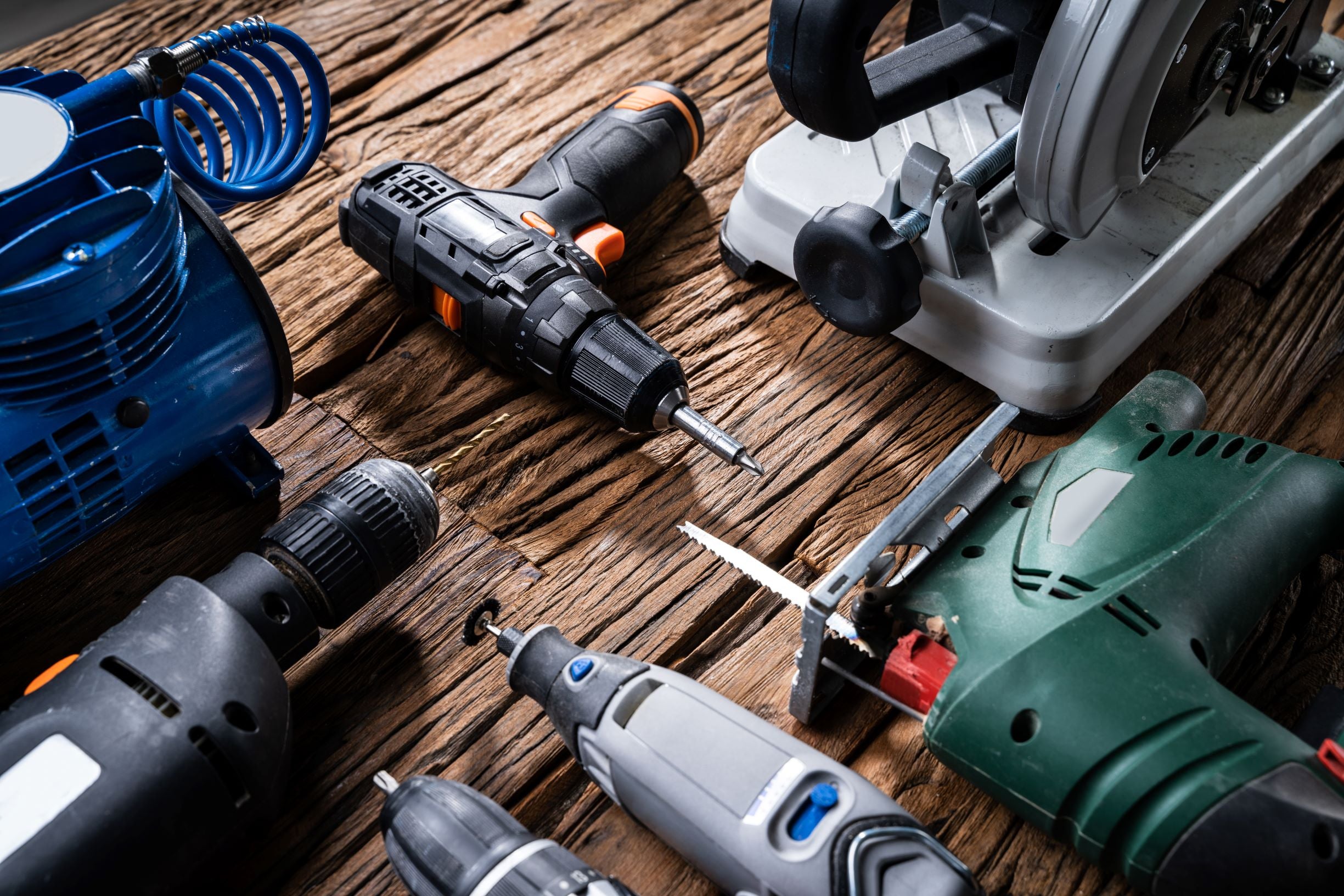 Several power tools for building laying on wooden floor.