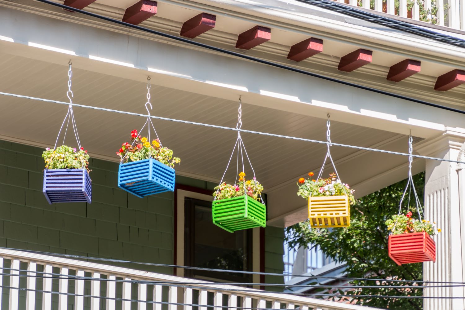 Reclaimed wooden boxes used as colorful planters in a porch.
