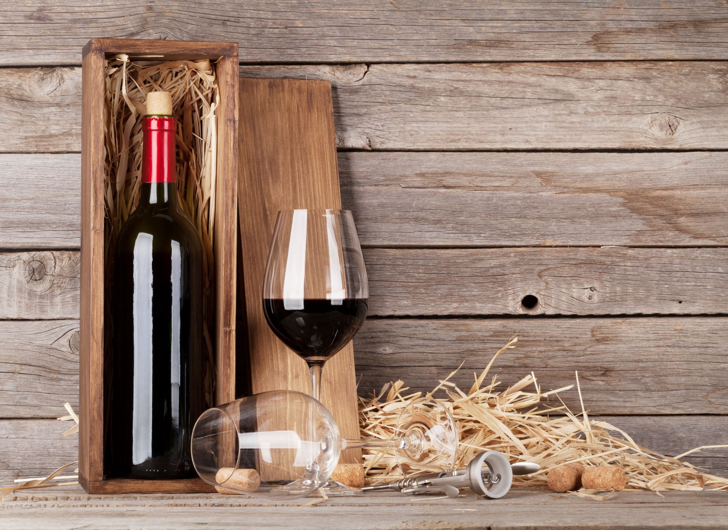 Wine bottle in a DIY wooden box next to a glass of wine.