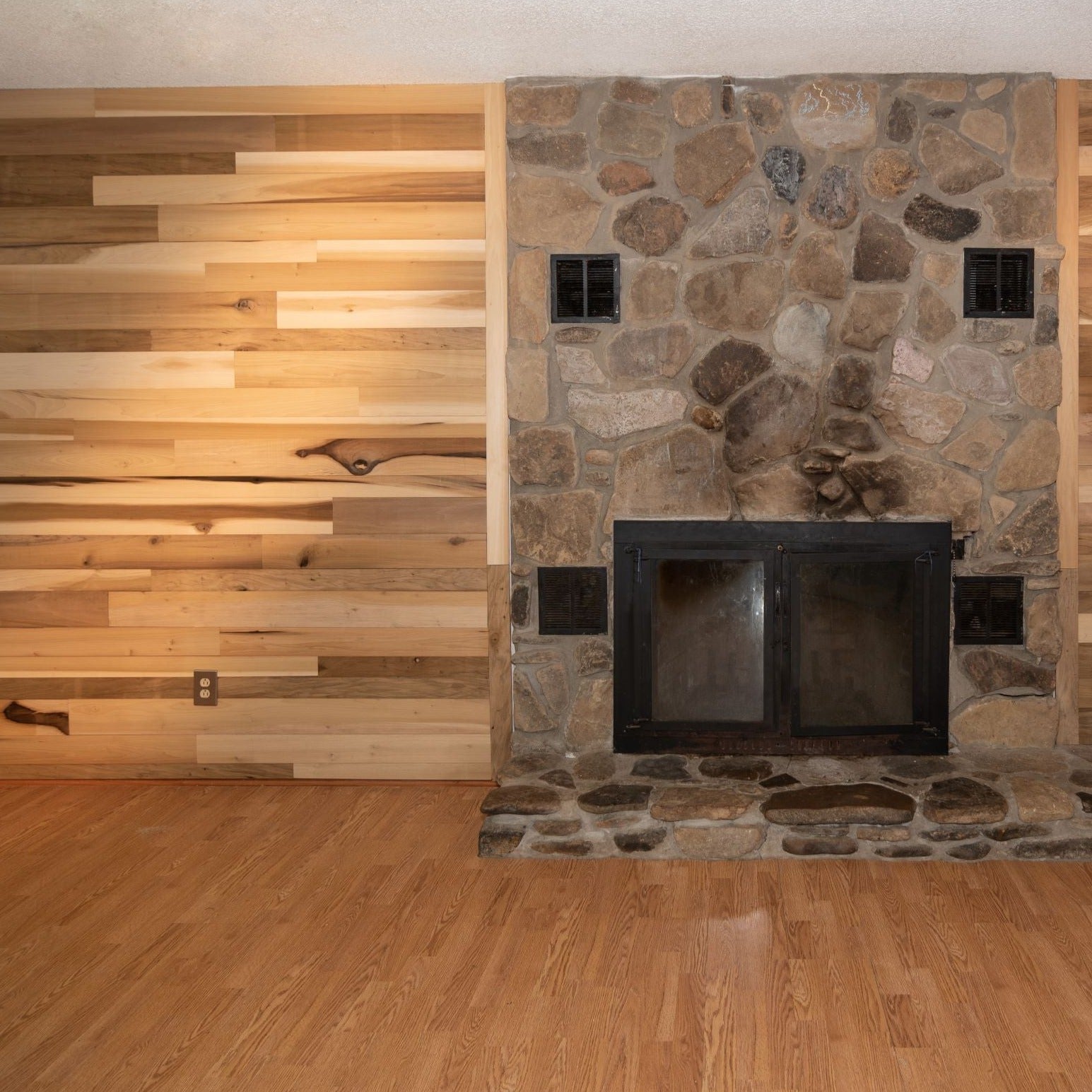 Reclaimed minteral poplar wooden living room wall with a stone fireplace.