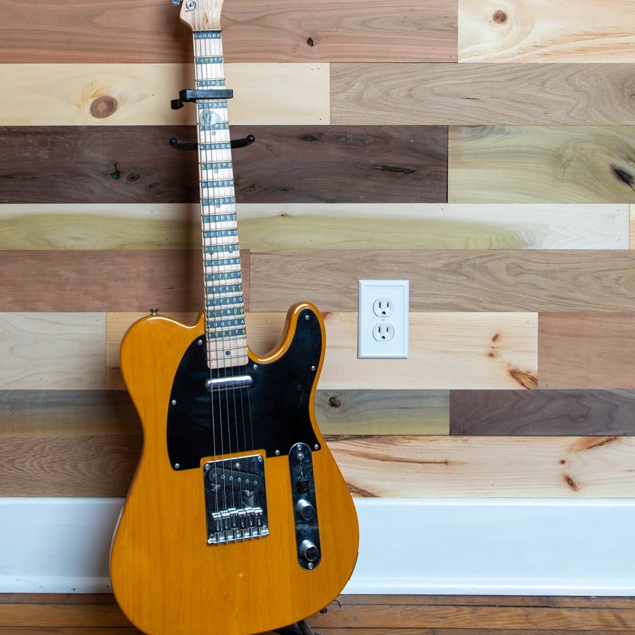 Vintage multicolored reclaimed wooden plank wall with a guitar leaning aganist it.